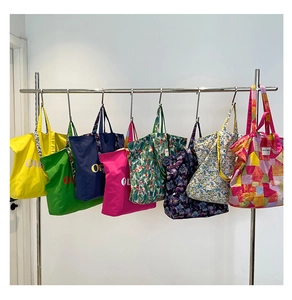 Close-up of various colorful canvas tote bags with prints hanging on a metal display rack