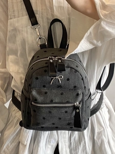 Mini gray quilted backpack with metal bow charm and adjustable straps on model