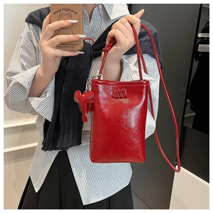 Detailed macro view of red patent leather crossbody bag with letter m and elephant charm