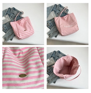 Detail view of striped canvas tote bag showing interior lining and metal logo