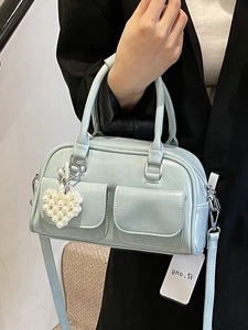 Light blue Boston handbag with pearl heart charm worn by model in black suit
