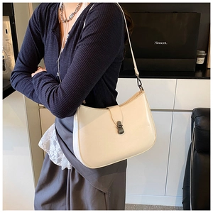 Close-up of minimalist cream underarm bag with oval metal buckle and smooth leather finish