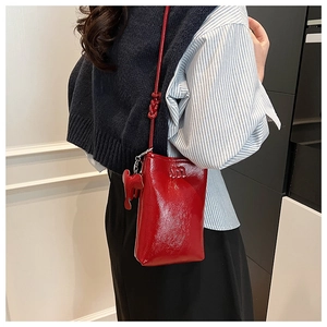 Detail of red patent leather crossbody phone bag with m logo and elephant charm