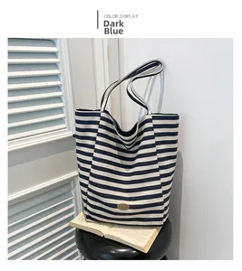 Close-up of navy blue striped canvas tote bag with oval metal plaque on white background