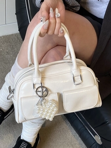 Glossy white Boston handbag with twin front pockets and pearl heart pendant charm