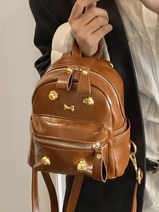 Brown PU leather backpack with gold puppy charms and rivet details on the front pocket