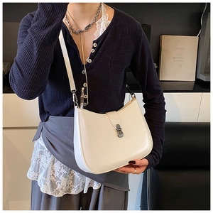 Detail of silver metal buckle on minimalist off-white hobo shoulder bag with smooth texture