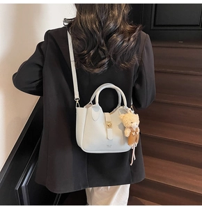 Dettaglio borsa in pelle azzurra con trama litchi, fibbia dorata e ciondolo orsetto