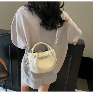 Detail einer beige Kordelzug-Beuteltasche mit elegantem Lederfinish und metallischen Perlen
