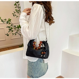 Detail of black silk handbag with floral patterns and amber beaded handle on a model