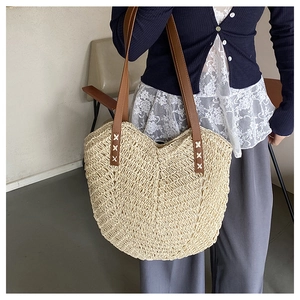 Detail of hand-woven straw tote bag featuring brown PU straps and delicate wave texture