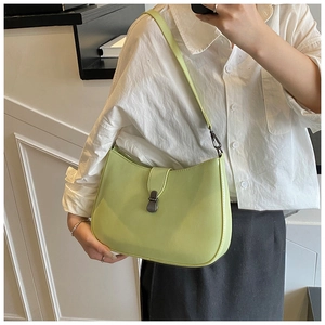 Detail view of a light green crescent shoulder bag on model with dark metal buckle