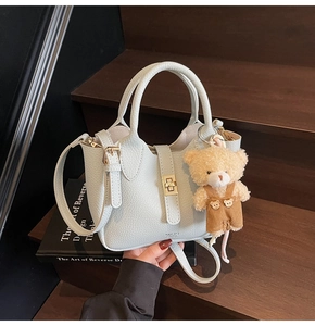 Dettaglio borsa a secchiello in pelle martellata con chiusura oro e ciondolo orso