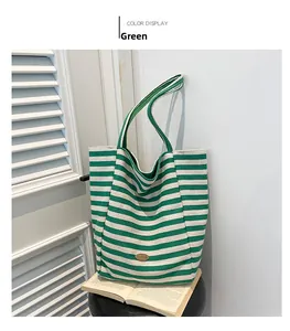 Close-up of green and beige striped canvas tote bag with retro oval nameplate on black stool