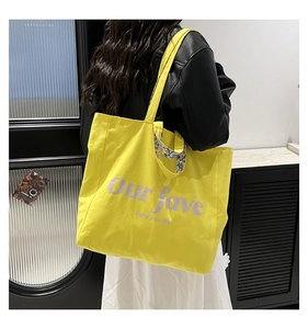 Detail of yellow canvas tote bag featuring floral pattern straps and purple lettering