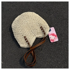 Detailed close-up of woven straw bag with premium brown leather straps and stitching