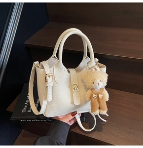 Dettaglio borsa a secchiello beige in pelle martellata con ciondolo a forma di orso