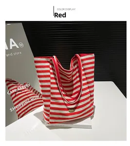 Close-up of red and white striped canvas tote bag with oval metal logo and red handles