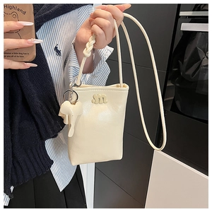 Detail of cream crossbody phone bag with litchi grain leather and elephant charm