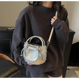 Detail der silbernen Metallic-Beuteltasche mit Ringgriff und verstellbarem Riemen
