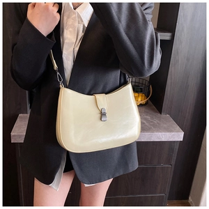 Detail of a cream faux leather underarm bag with vertical strap and metal buckle