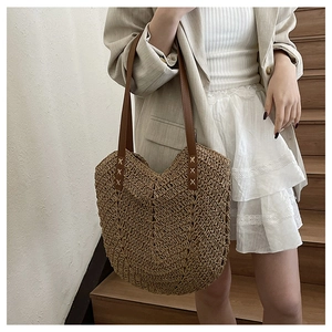 Detail of handwoven straw tote bag with V-shaped texture and reinforced leather straps