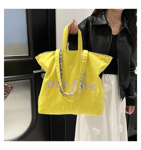 Detail of yellow canvas tote bag featuring purple lettering and floral printed shoulder straps