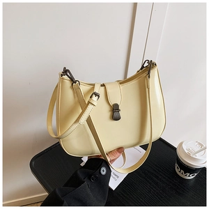 Detail view of beige PU leather crescent bag with bronze buckle and slender strap