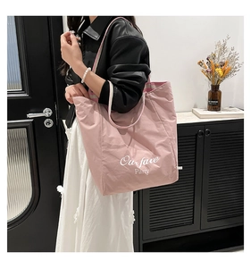 Detail view of large pink tote bag featuring a woven strap and Our Fave Party text print