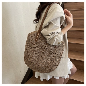 Detail of hand-stitched leather strap on natural woven straw tote bag for summer