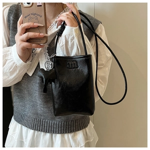 Detail of black glossy mini crossbody bag with metal m logo and elephant charm
