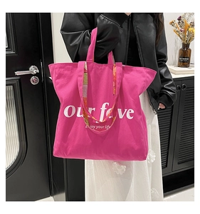 Detail of hot pink canvas tote bag featuring unique dual straps and white typography