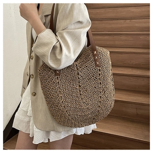 Close-up of woven straw tote bag featuring detailed V-shape texture and leather straps