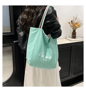 Detail of mint green tote bag with Our fave Party print and pink inner lining