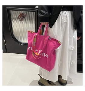 Detail showing the 'our five' logo print on a rose pink canvas tote bag carried by a model