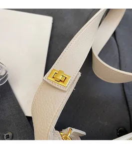Detailed macro view of the golden swivel metal lock on white lychee pattern leather bag