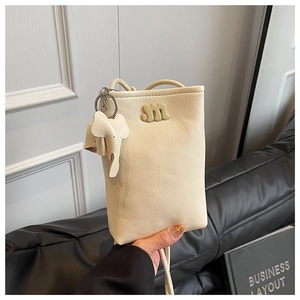 Creamy mini crossbody bag with gold m logo and cute elephant pendant detail