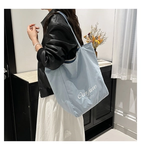 Detail of light blue tote bag featuring white Our fave Party print worn by a model