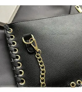 Close-up of black litchi grain leather bag with high-gloss gold chain and hardware