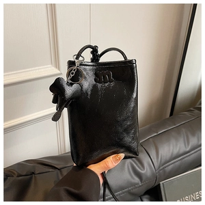 Detail of black glossy mini crossbody bag with embossed M logo and heart charm