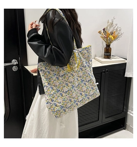 Close-up of a floral print tote bag with yellow straps shown in a lifestyle setting