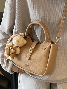 Elegante borsa a secchiello marrone motivo litchi con ciondolo a orsetto e oro