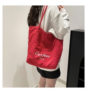Detail of red tote bag with white Our fave Party text print on smooth fabric surface