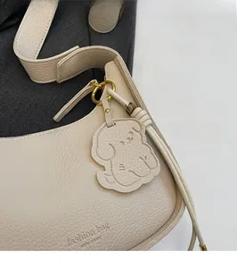 Detail of lychee pattern leather shoulder bag with cute dog pendant and metal beads