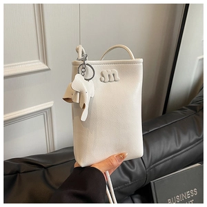 Close-up of white leather phone bag with 3D elephant charm and letter M detail