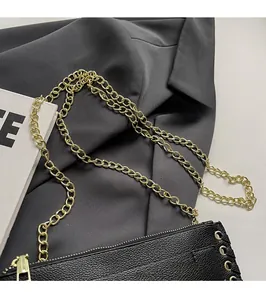 Close-up of black lychee grain leather bag with gold chain strap and metal logo detail