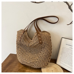 Detail view of the wave-pattern straw weaving and brown leather handle with X-shaped stitching