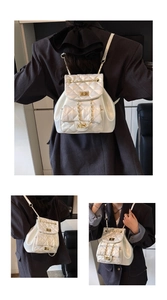 Detail view of white quilted backpack with gold turn-lock closure and chain straps