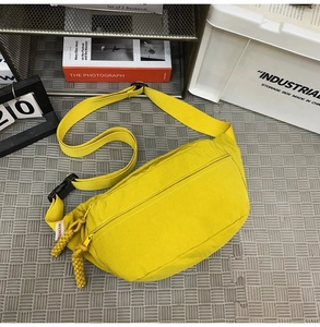 Dettaglio del borsello monospalla in nylon giallo con cerniere in corda e etichetta laterale