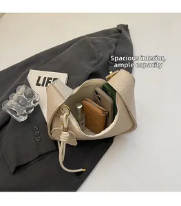 Spacious interior of beige lychee leather crescent bag holding phone and perfume